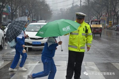 暖心 高峰时段,一位学生为执勤民警撑伞遮雨